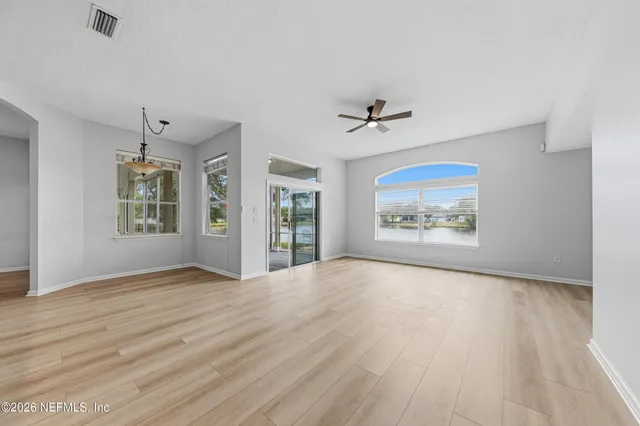 a view of an empty room with a window and wooden floor
