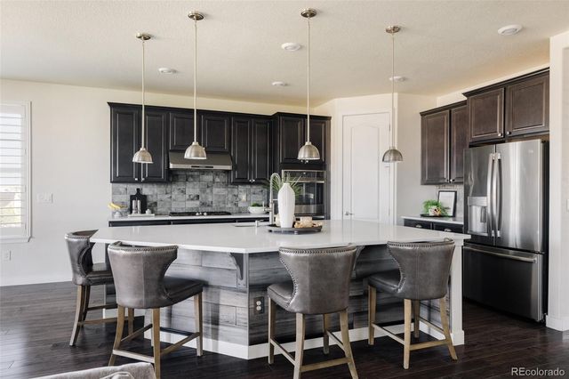a kitchen with stainless steel appliances a dining table chairs sink and cabinets