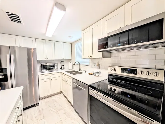 a kitchen with stainless steel appliances a stove a sink a refrigerator and cabinets