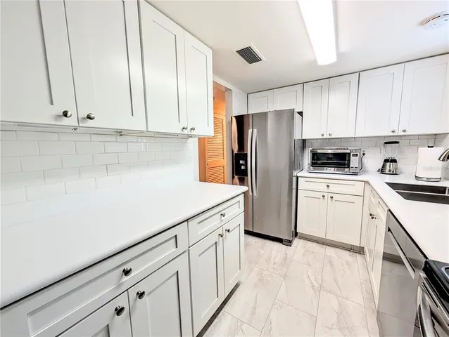 a kitchen with white cabinets and white appliances
