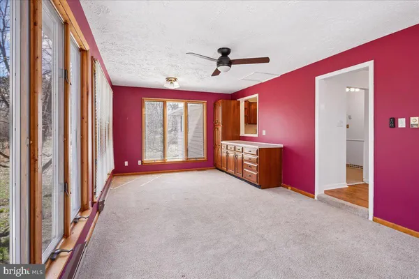 a view of an empty room with window and a kitchen