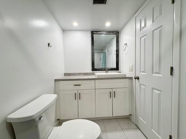 a bathroom with a granite countertop toilet sink and mirror