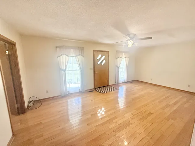 an empty room with wooden floor and windows