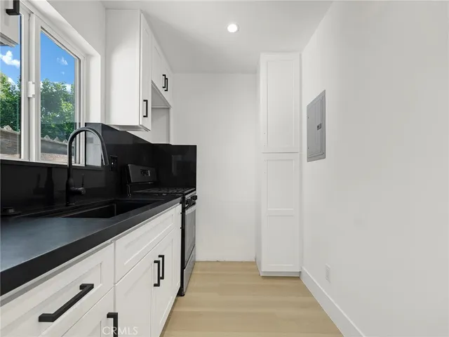 a kitchen with granite countertop white cabinets and black appliances