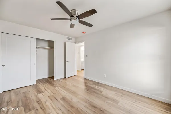 an empty room with wooden floor and ceiling fan
