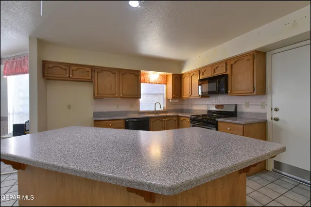 a kitchen with stainless steel appliances granite countertop white cabinets and a stove top oven