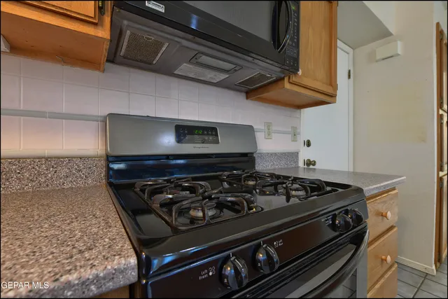 a view of an empty room with chandelier fan and wooden floor