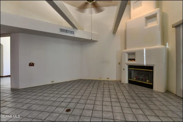 an empty room with a chandelier fan and windows