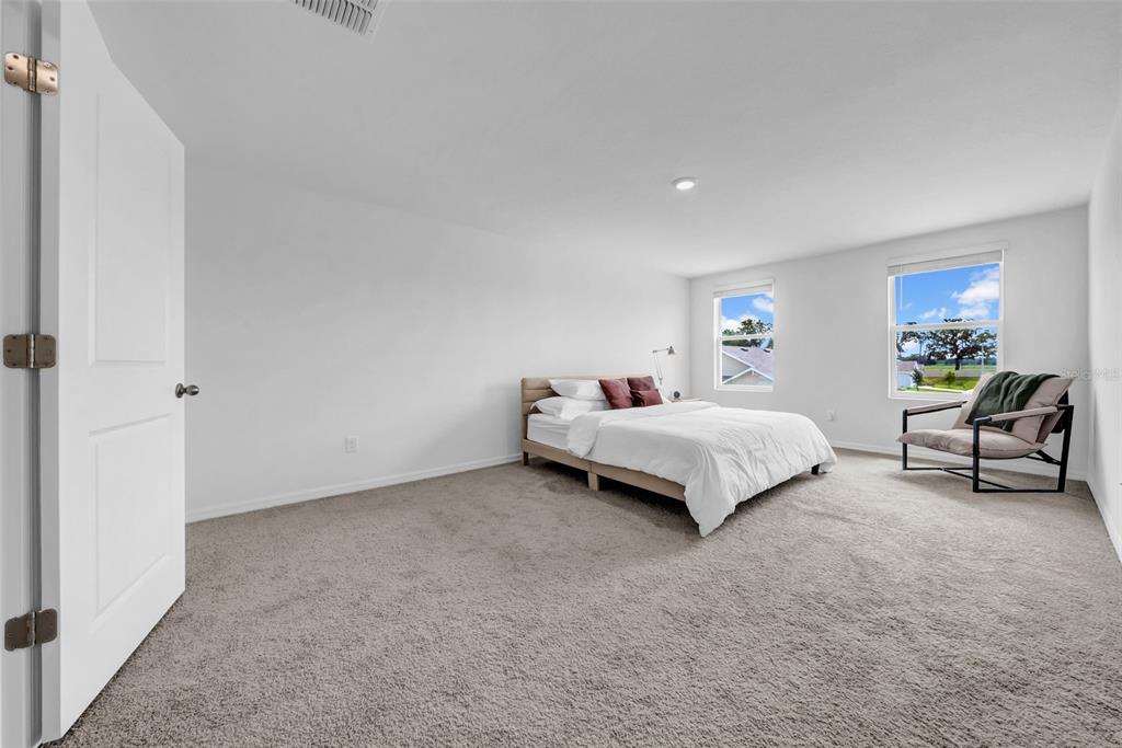 13295 Mylion Way Spring Hill, FL 34610 - Photo 34 of 68 a spacious bedroom with a bed and a couch