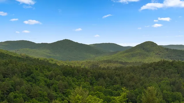 a view of a mountain range with lush green forest