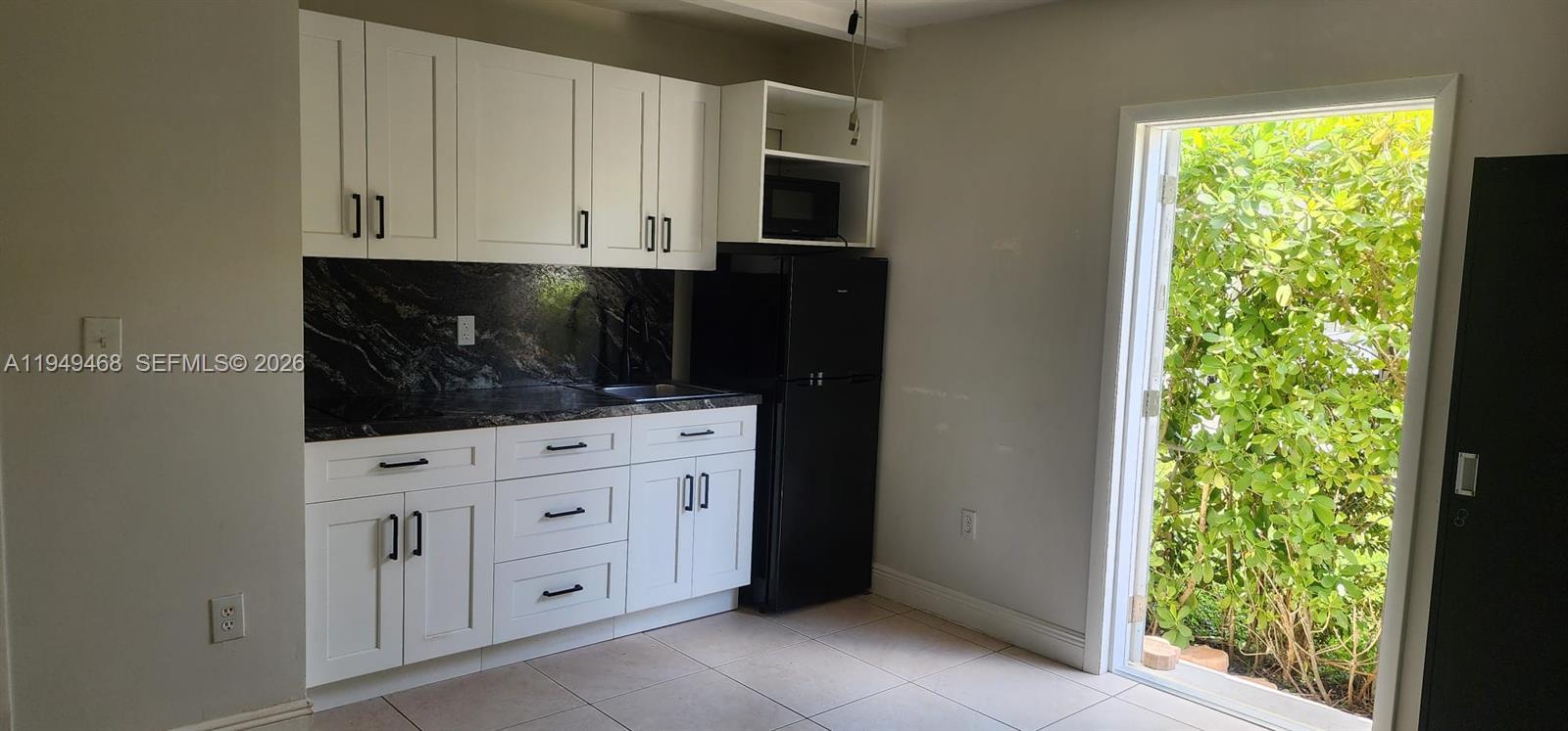 6265 Southwest 31st Street, Unit B Miami, FL 33155 - Photo 15 of 26 a kitchen with white cabinets and a window