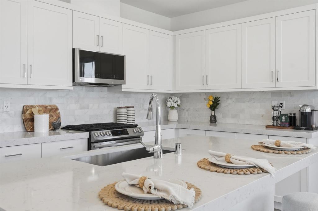2402 Cascalote Loop San Diego, CA 92154 - Photo 6 of 35 a kitchen with white cabinets and appliances
