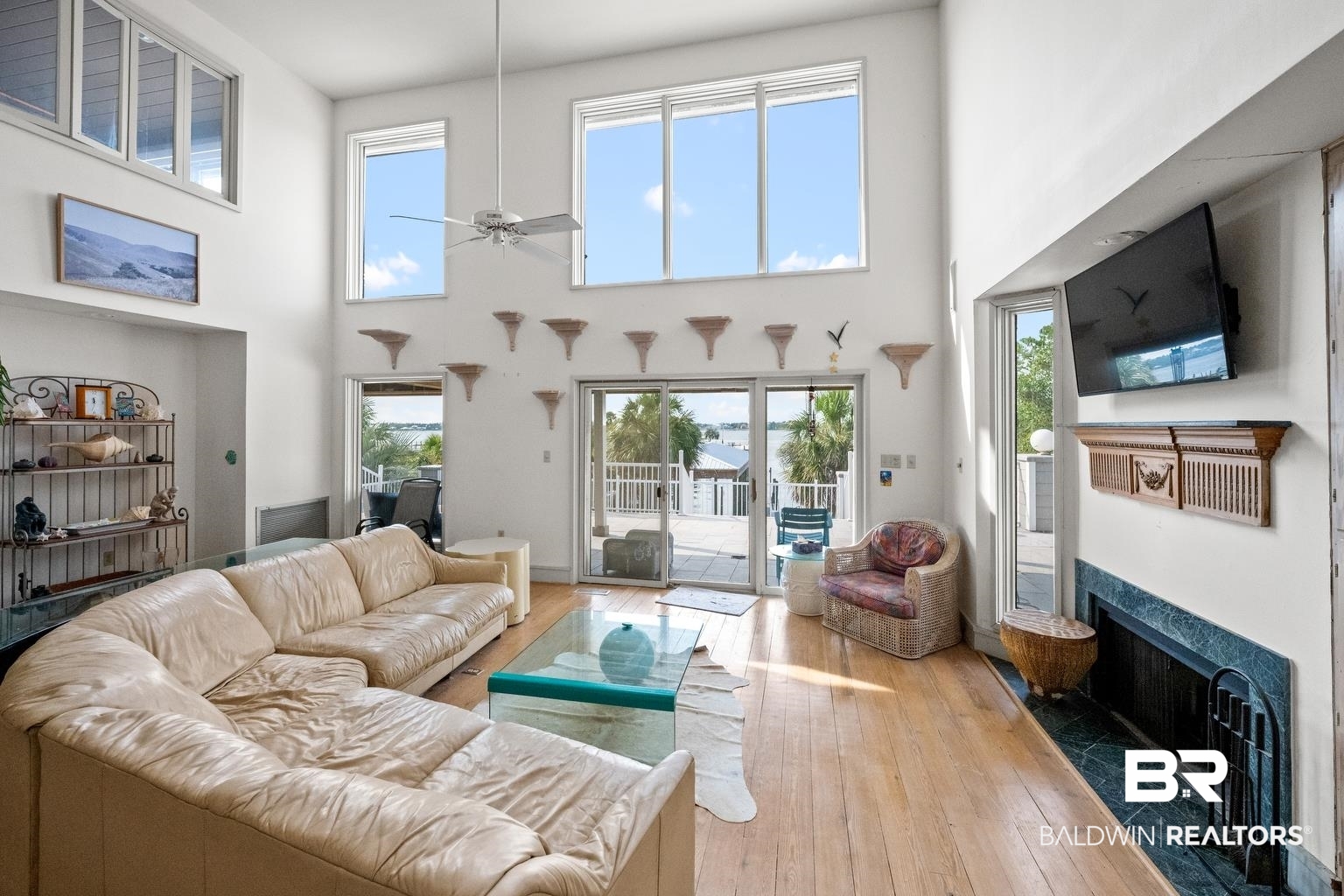 29255 Ono Boulevard Orange Beach, AL 36561 - Photo 20 of 43 Living room featuring a fireplace, a ceiling fan, hardwood / wood-style floors, and a towering ceiling