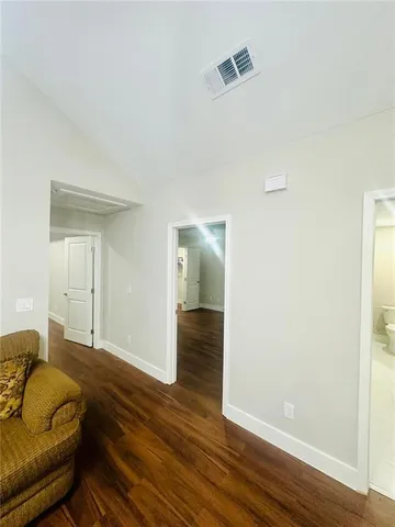 a living room with stainless steel appliances furniture a fireplace a flat screen tv and a wooden floor