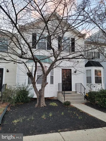 a view of a white house with a large tree