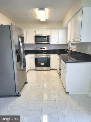 a kitchen with granite countertop a refrigerator and a stove top oven