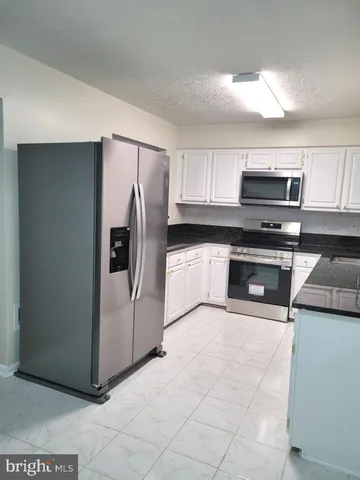 a white kitchen with granite countertop white cabinets and stainless steel appliances
