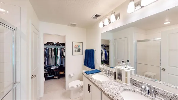 a bathroom with a granite countertop sink a toilet a mirror and shower
