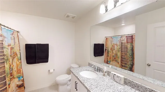 a bathroom with a granite countertop sink a mirror and a toilet