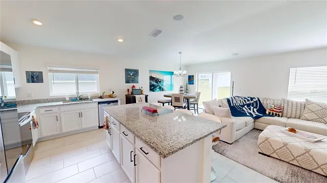a open kitchen with granite countertop a sink and white cabinets