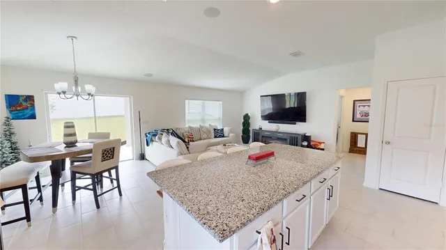 a view of a dining room and livingroom with furniture wooden floor a rug a flat screen tv a rug a fireplace and a chandelier