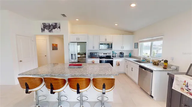 a kitchen with stainless steel appliances granite countertop a stove a sink a microwave a center island and a refrigerator