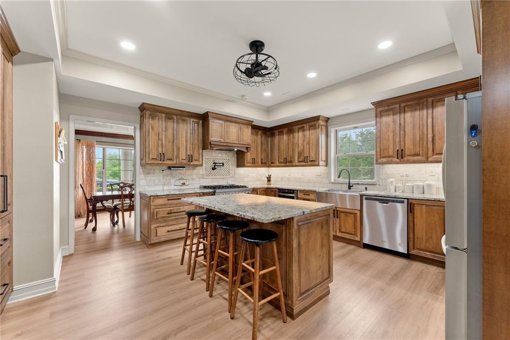 7215 Kelly Bridge Road Dawsonville, GA 30534 - Photo 37 of 87 a kitchen with stainless steel appliances granite countertop a stove top oven a refrigerator a sink and a dining table with wooden floor