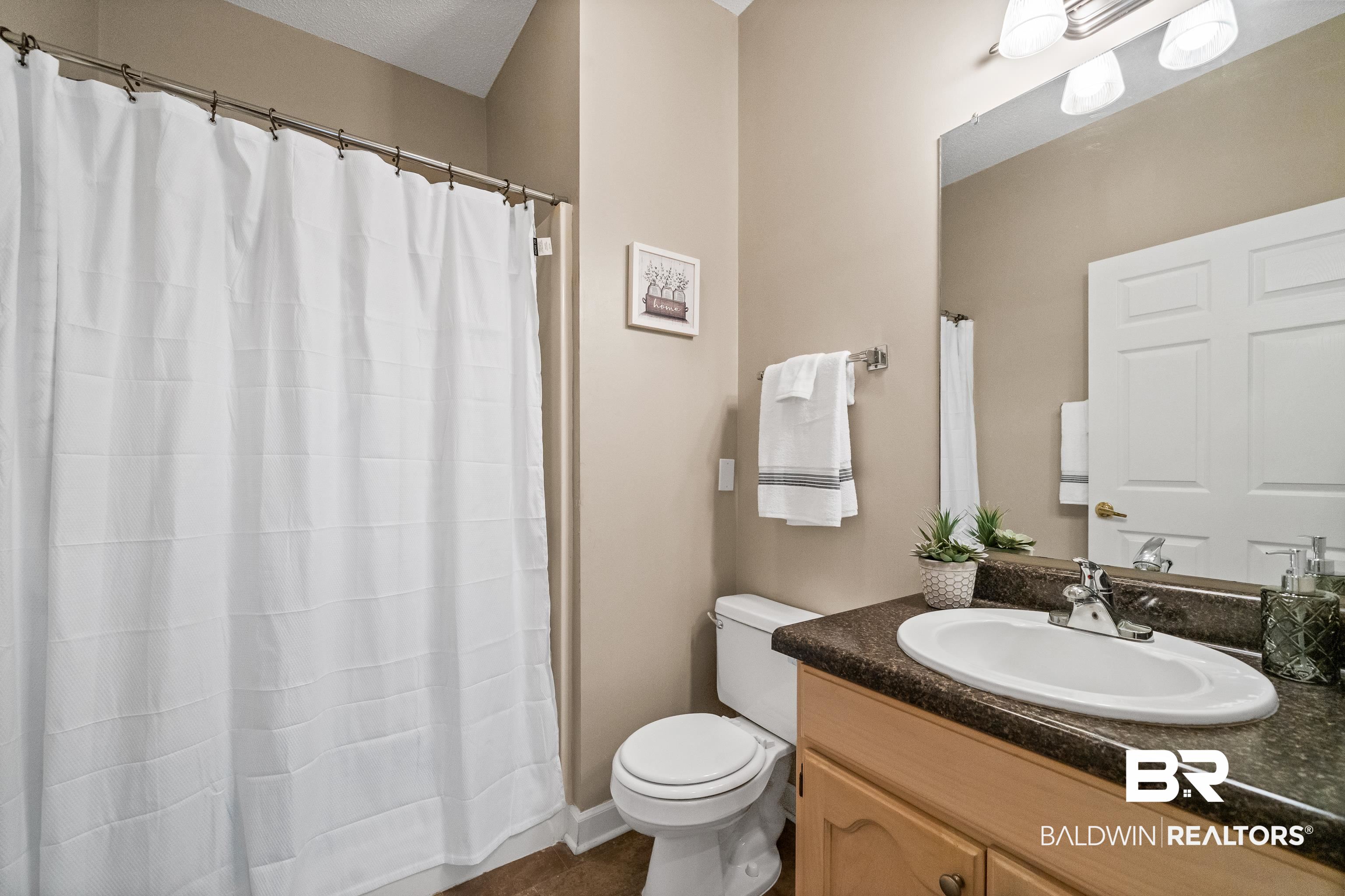 27 Cottage Drive Fairhope, AL 36532 - Photo 25 of 33 Bathroom with vanity, a shower with shower curtain, and dark tile patterned flooring