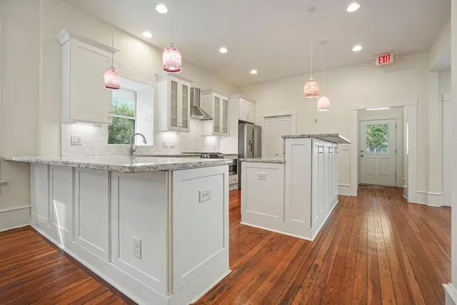 a kitchen with kitchen island granite countertop a sink cabinets and wooden floor