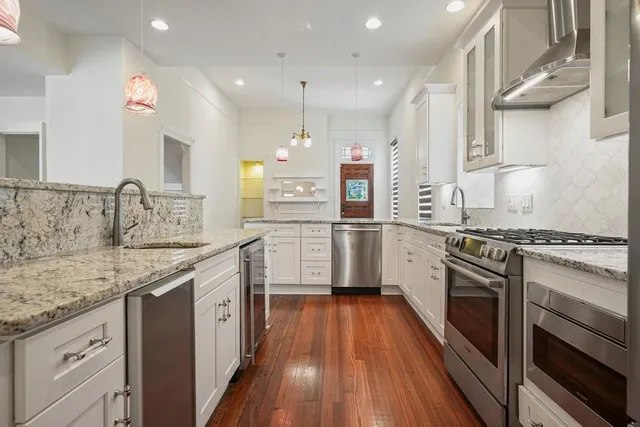 a kitchen with a sink stove cabinets and wooden floor