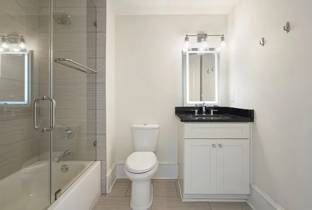 a bathroom with a granite countertop sink a toilet and shower