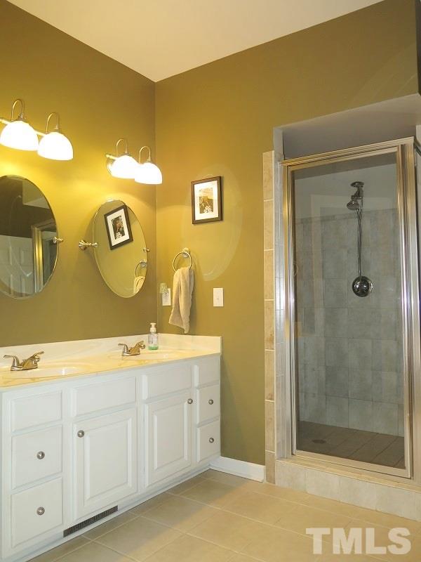 7801 Housewren Place Raleigh, NC 27613 - Photo 14 of 23 a spacious bathroom with a double vanity sink and mirror