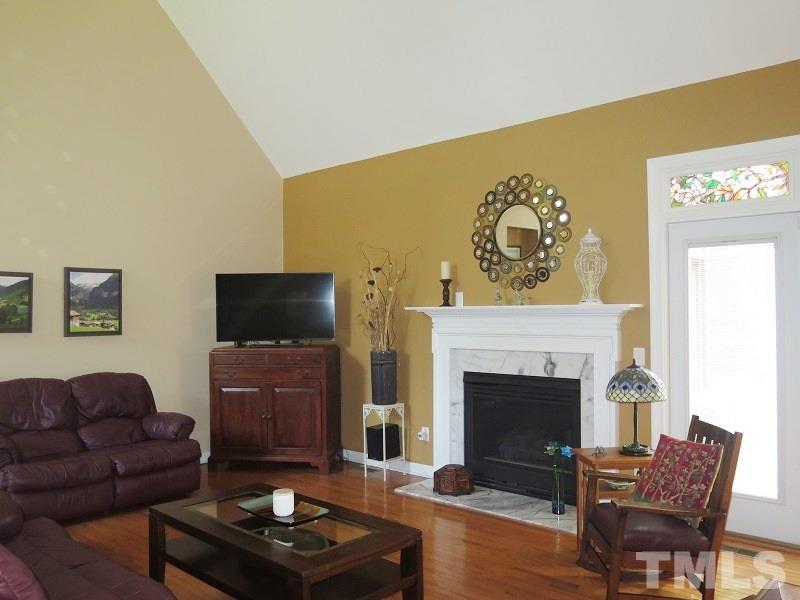 7801 Housewren Place Raleigh, NC 27613 - Photo 4 of 23 a living room with furniture a flat screen tv and a fireplace