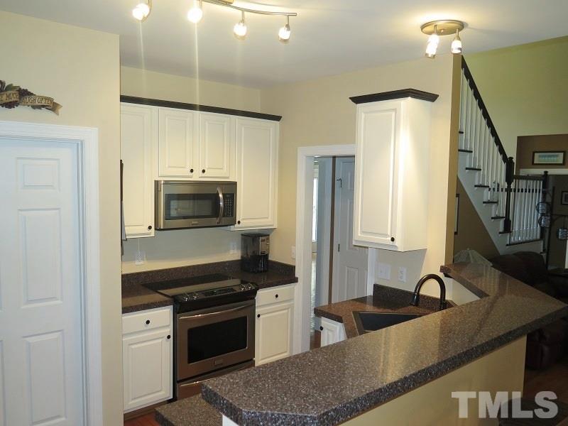 7801 Housewren Place Raleigh, NC 27613 - Photo 8 of 23 a kitchen with stainless steel appliances granite countertop a sink stove and refrigerator