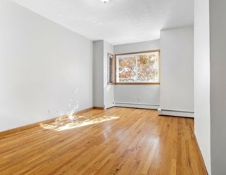 156 Lexington Street, Unit 1 Boston, MA 02128 - Photo 9 of 12 an empty room with wooden floor and windows
