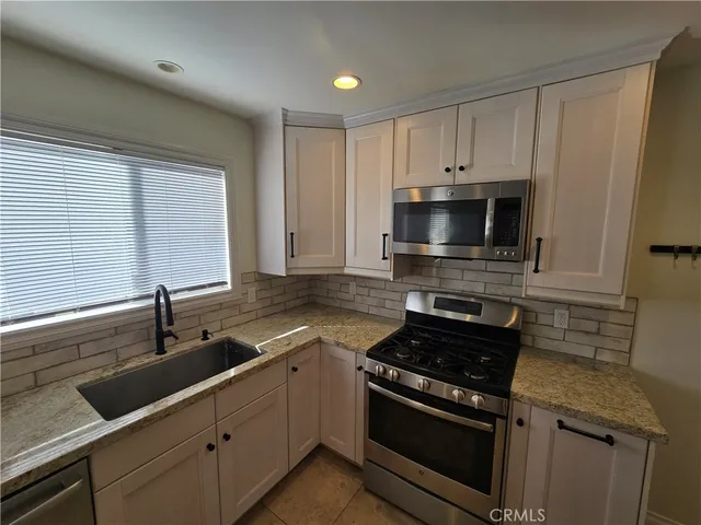 a kitchen with granite countertop a sink stainless steel appliances and cabinets