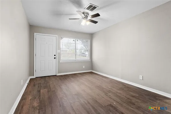 an empty room with wooden floor and windows