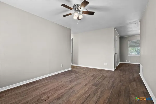 a view of an empty room with window and wooden floor