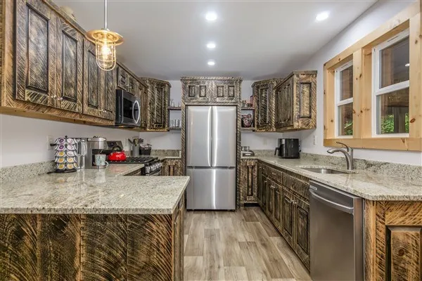 a kitchen with stainless steel appliances granite countertop a sink refrigerator and cabinets