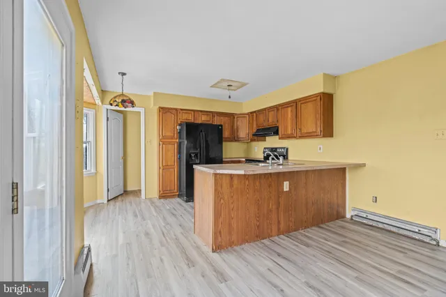 a view of kitchen with stainless steel appliances granite countertop a refrigerator a sink dishwasher and wooden cabinets with wooden floor