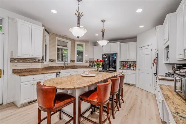 a kitchen with stainless steel appliances granite countertop a stove a sink a stove a dining table and chairs