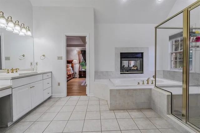 a spacious en suite bathroom with a double vanity sink a mirror and a bathtub