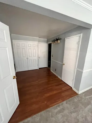 an empty room with wooden floor and entrance