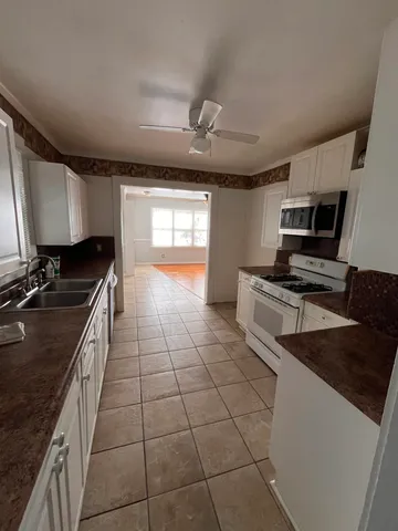a kitchen with granite countertop a stove a sink dishwasher and a microwave