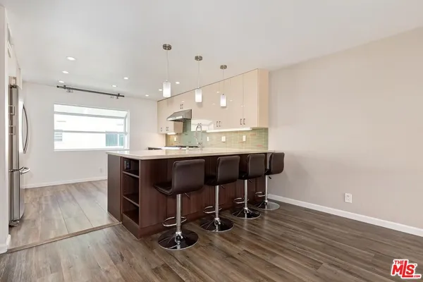 a kitchen with kitchen island stainless steel appliances a dining table chairs and sink