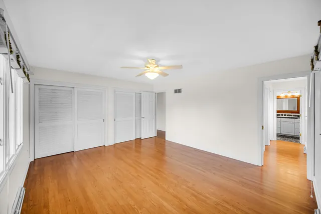 a view of an empty room with window and wooden floor