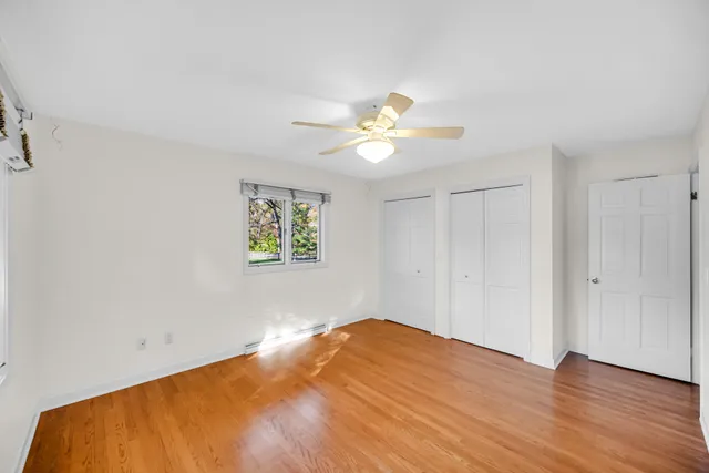 a view of an empty room with window and wooden floor
