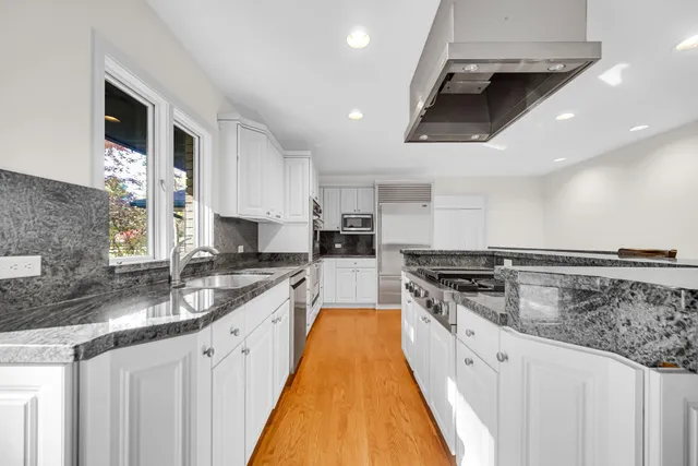 a room with stainless steel appliances a dining table chairs and a large window