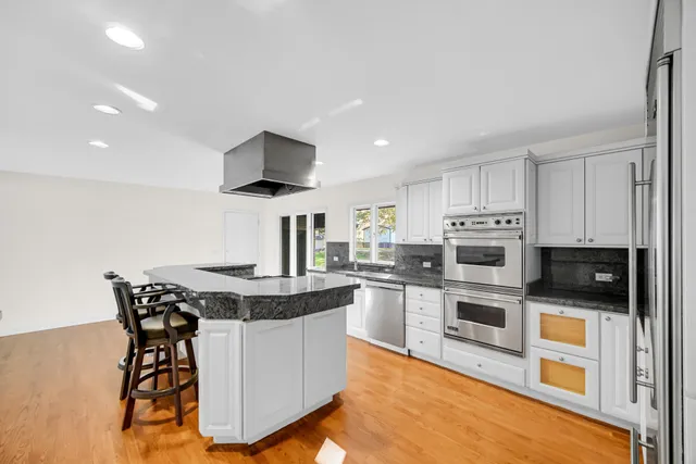a kitchen with stainless steel appliances granite countertop a table and chairs in it