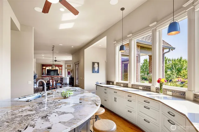 an open kitchen with granite countertop a stove a sink a dining table and chairs with wooden floor